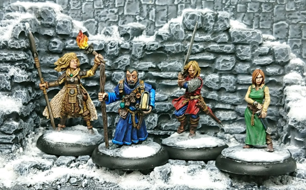 Photograph of a warband of model warriors - a woman dressed in furs with spear and torch, a man in a blue robe with staff and book, a male warrior with sword, and a woman in a long green dress, drawing a dagger