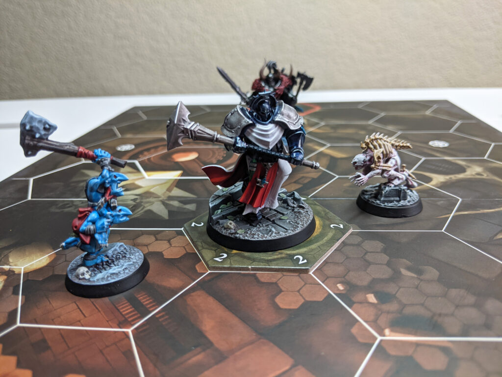 A close-up of some Underworlds fighters during a game of Arena Mortis. A Stormcast Eternal is in the centre, with a Gnoblar on his left, and a Ghoul on his right.