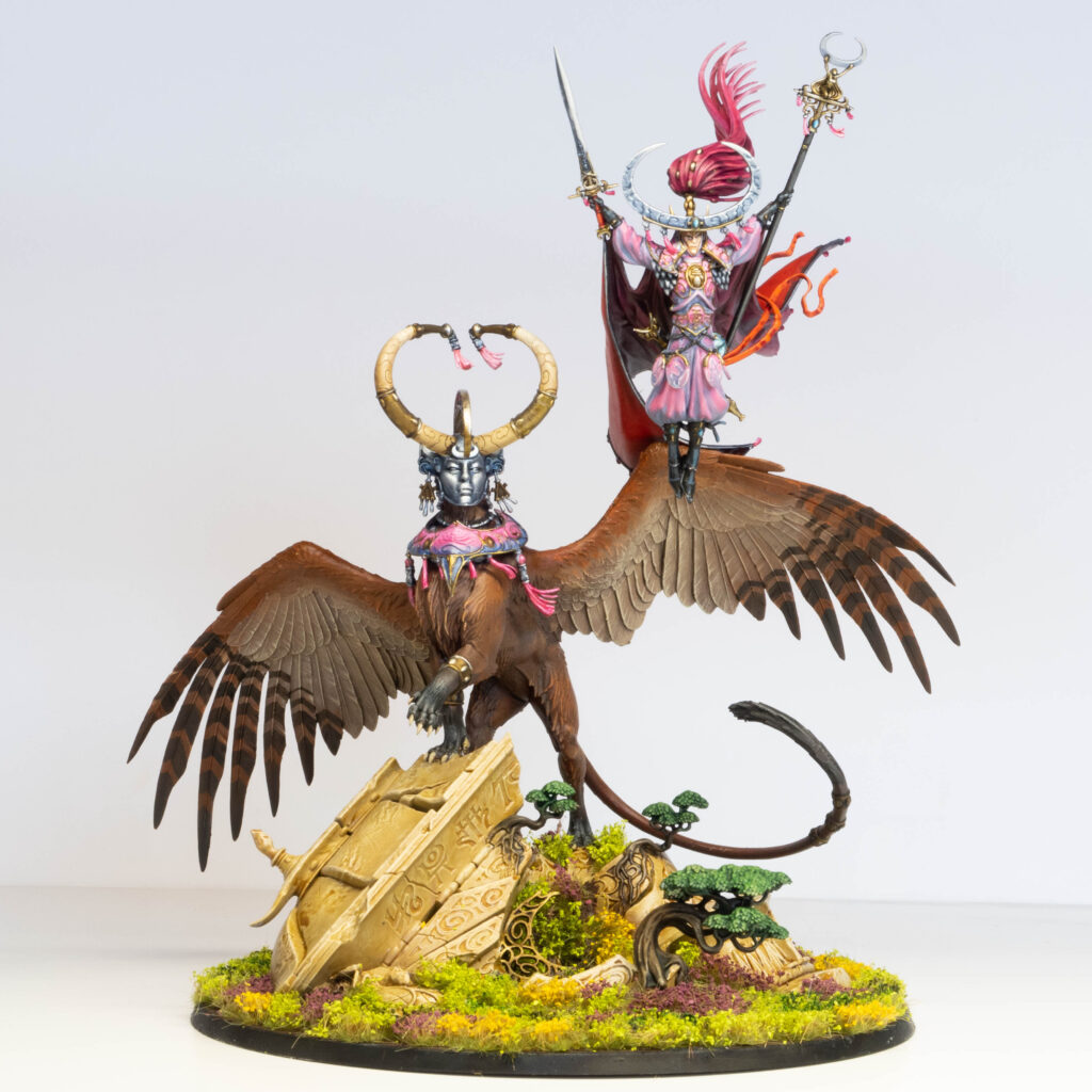 A painted model of an elf and its flying mount. The elf is painted pink, and the mount is brown.