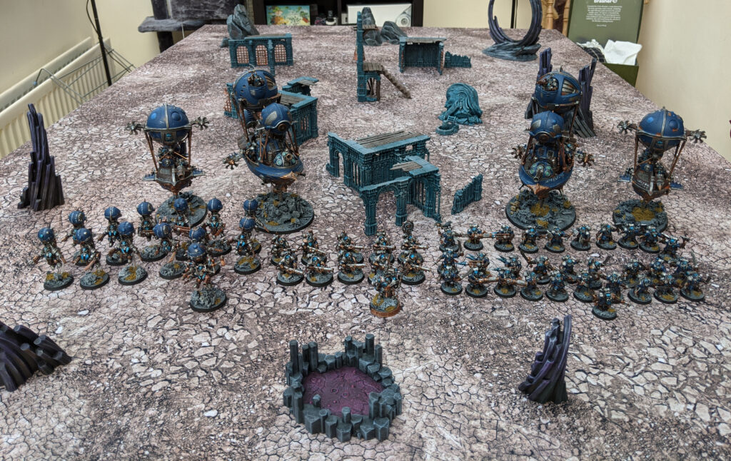 A Kharadron Overlords army, painted in a blue colour scheme, laid out on a gaming table.