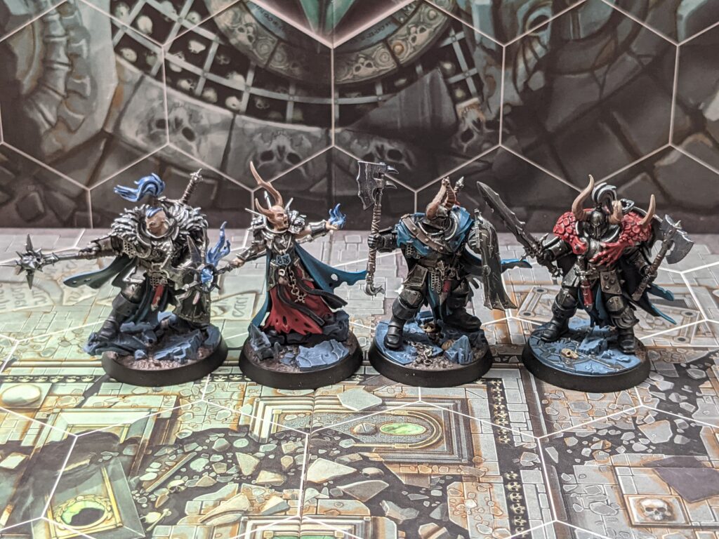 Four chaos warrior models, painted with shiny black armour, and blue cloaks.