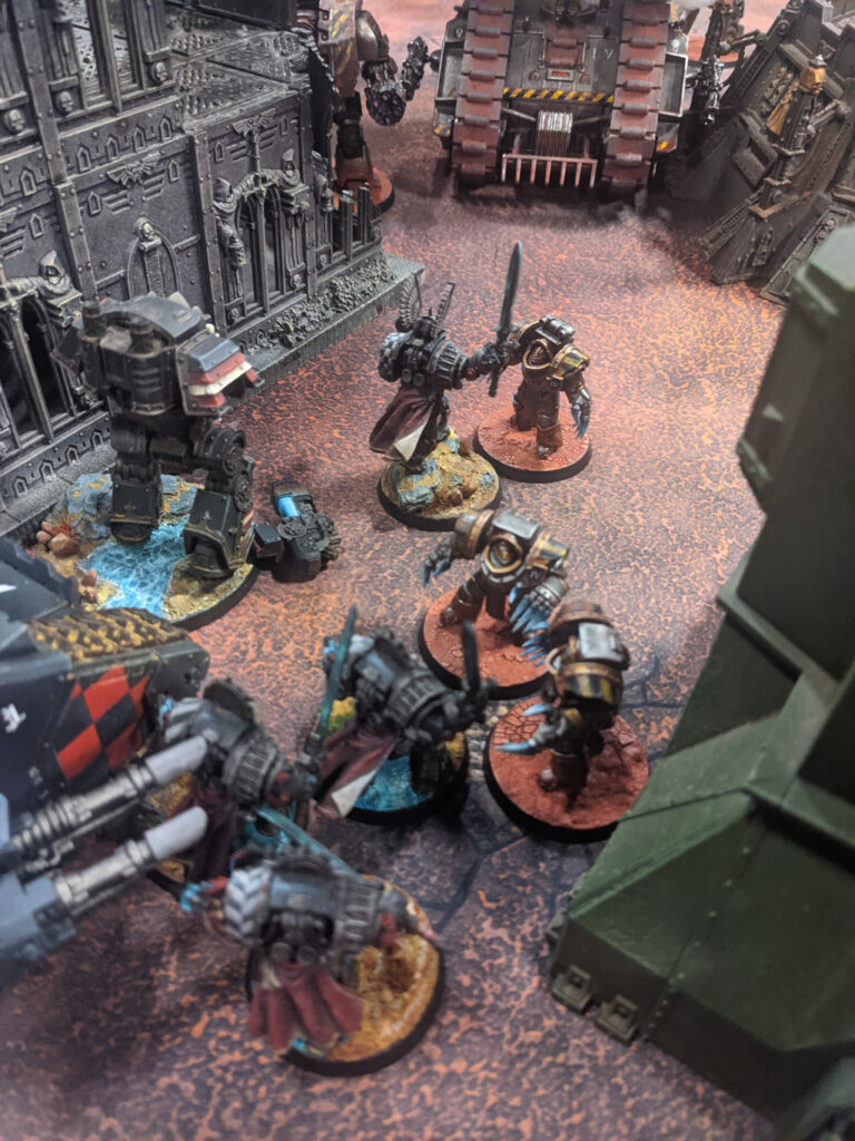 Units from the dark angels (black) and the iron warriors (metal with hazard stripes) clash on the tabletop