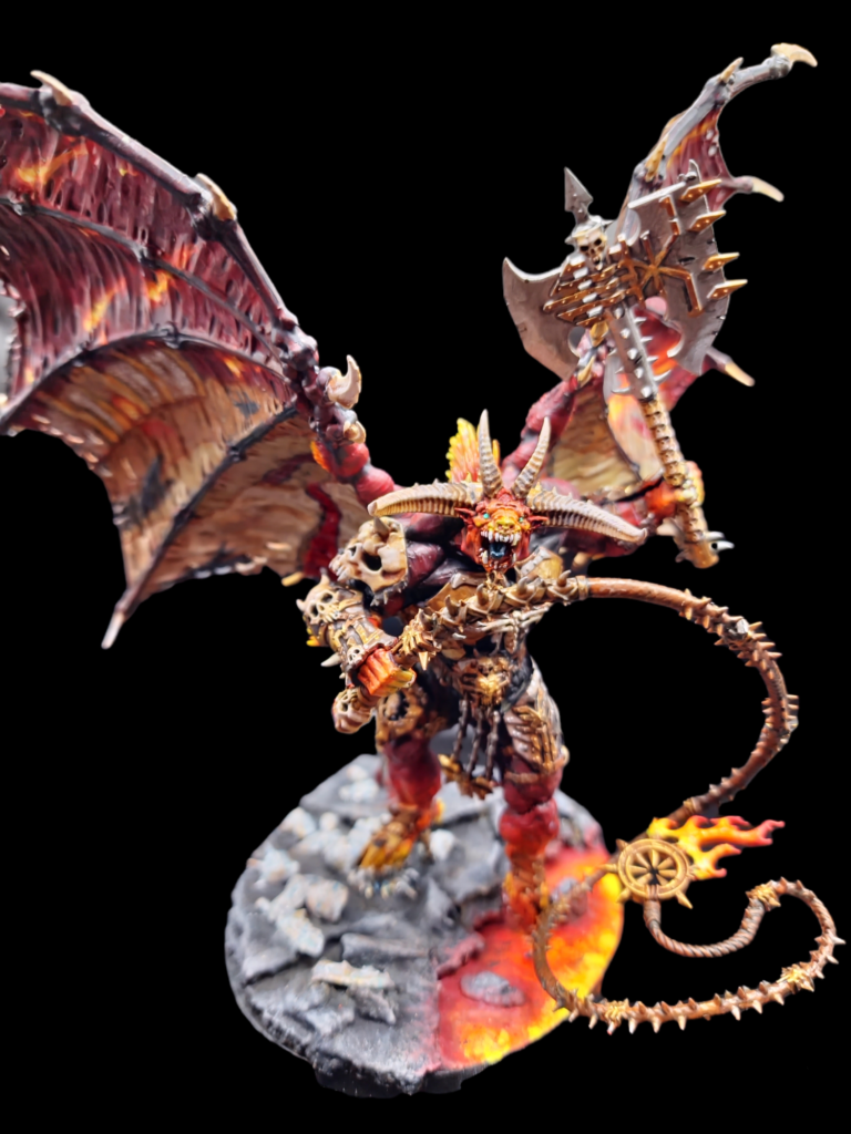 Bloodthirster of Unfettered Fury from the front, stood on rocks and lava.  It's wings have a painting on them of a hell landscape. Front view.