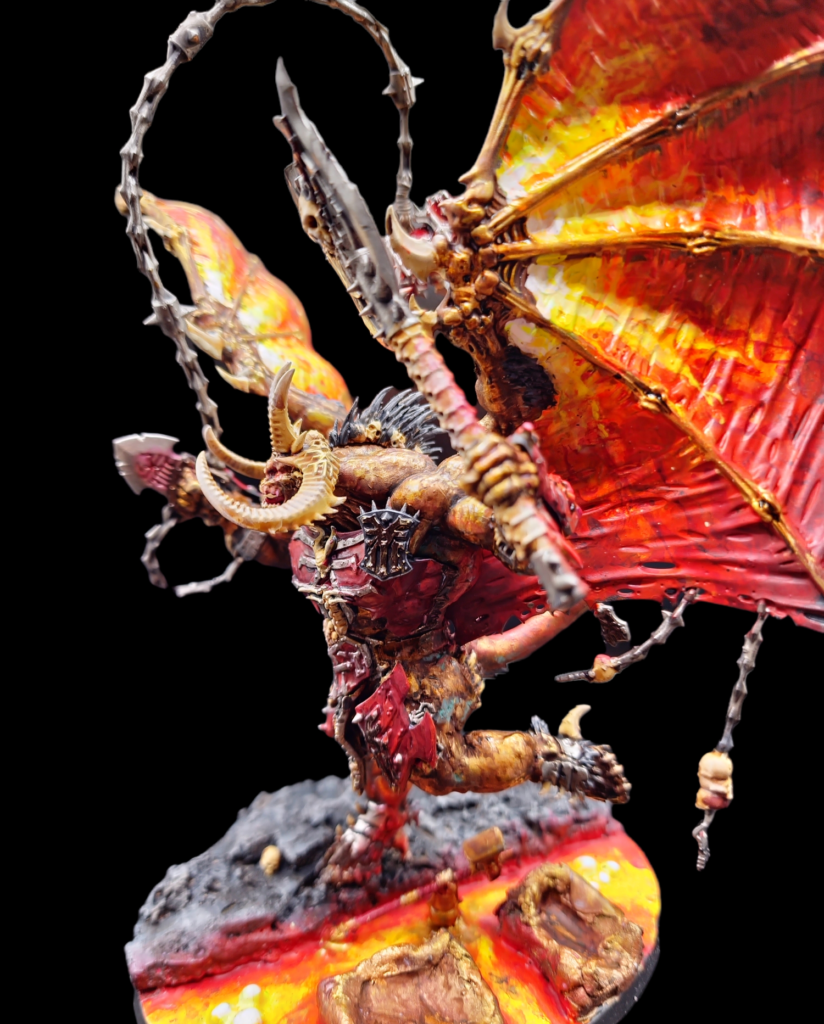 Wrath of Khorne Bloodthister from the side. Running pose, stood on rocks with some brass sigil and lava also present. It's wings are painted to be flames. 