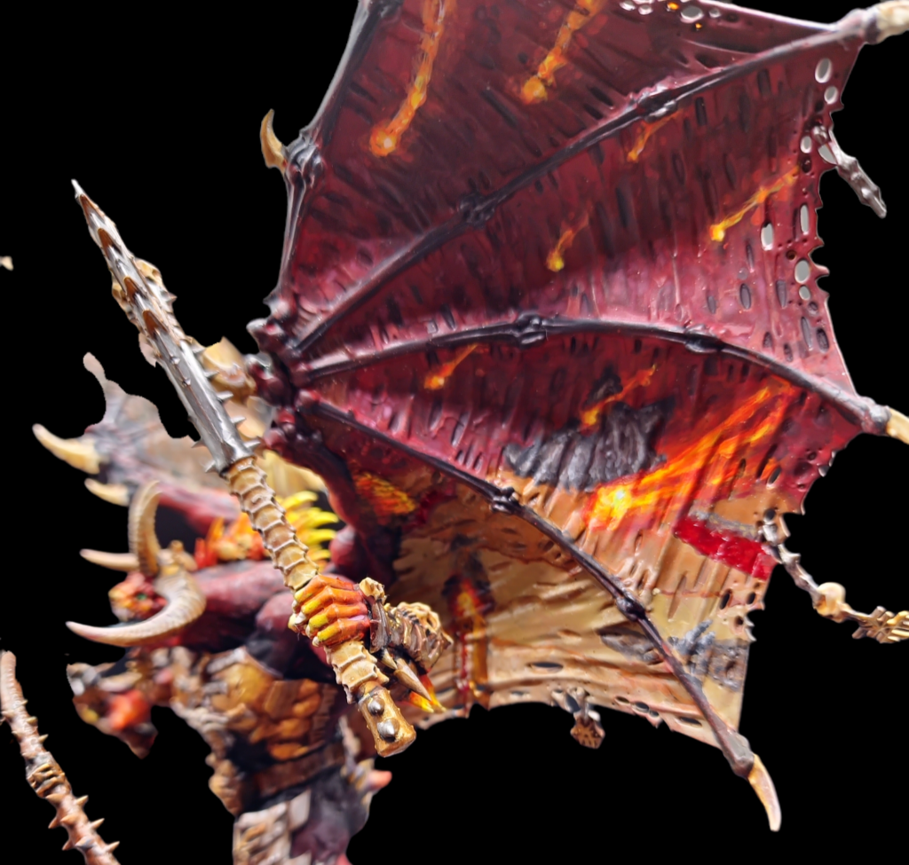 Bloodthirster of Unfettered Fury from the front, stood on rocks and lava.  It's wings have a painting on them of a hell landscape. Side view close up on a wing.